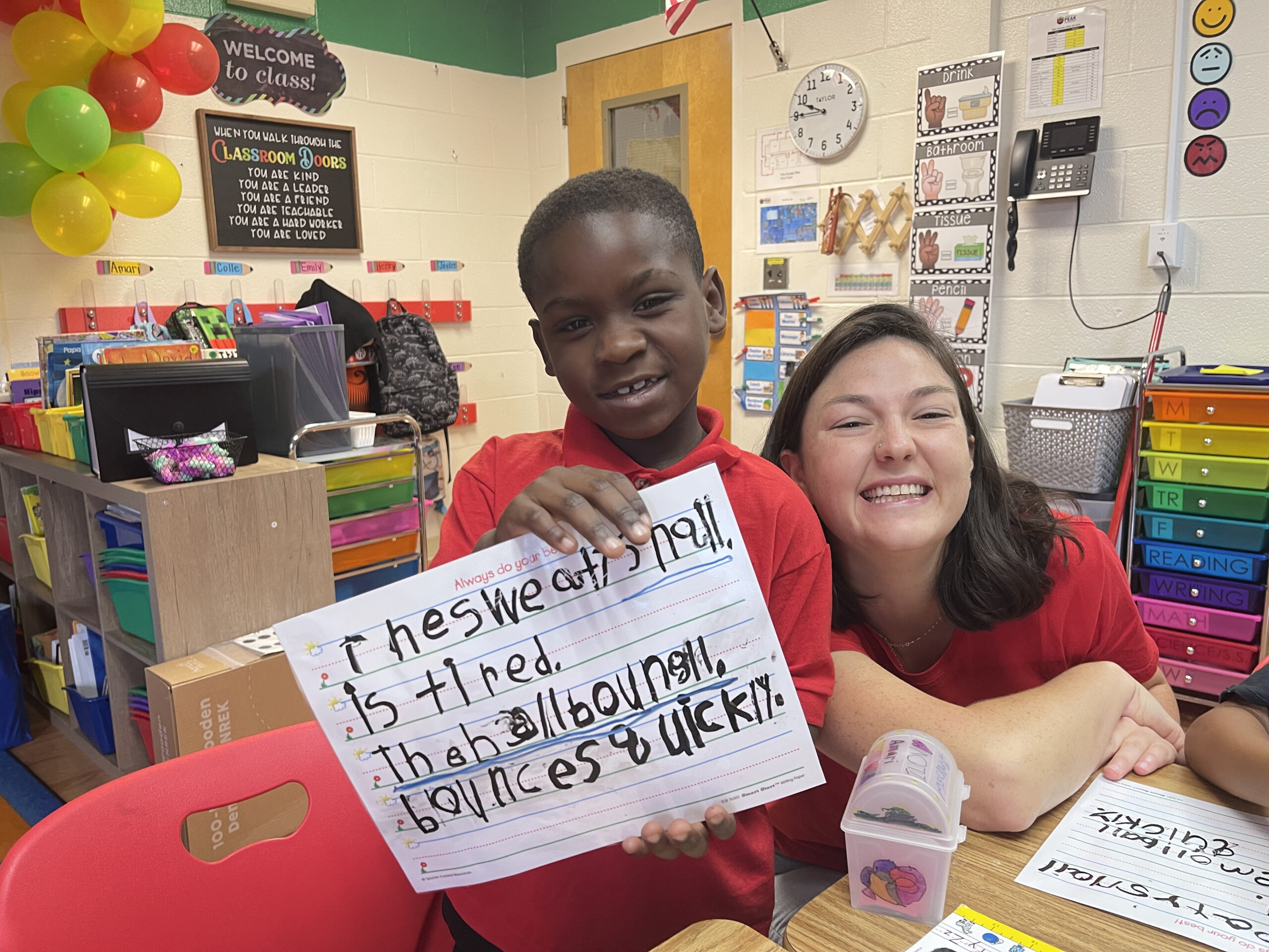 Black child with Caucasian teacher showing his schoolwork