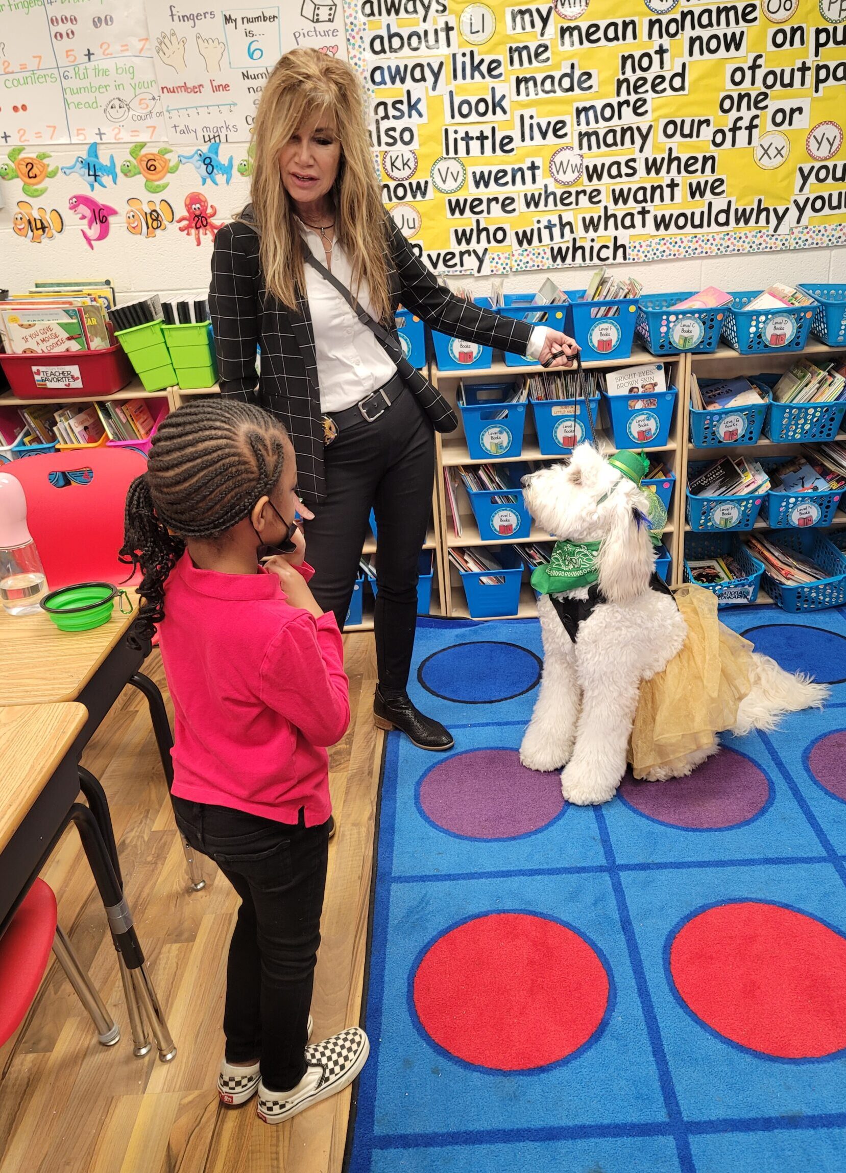 Caucasian lady with dog with black child in classroom for show and tell