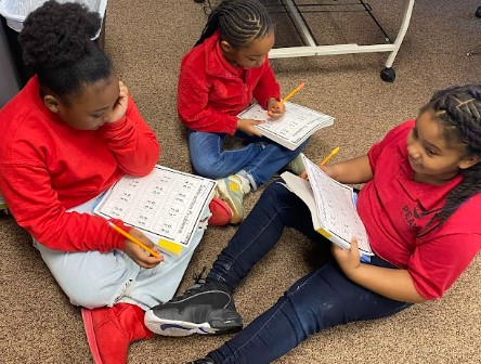 Group of black kids sitting on floor reading school books